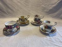 Four Paragon china teacup and saucer sets arranged with floral patterns and gold trim against a neutral background