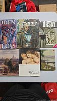 Overview of 5 art books and 1 magazine featuring covers with artworks and artists names including Cézanne, Courbet, Seurat, and Orsay Museum.