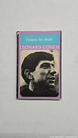 Front cover showing the title 'Flowers for Hitler' and a black-and-white portrait of Leonard Cohen on a purple background.