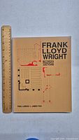 Front cover of the book titled 'Frank Lloyd Wright Between Principle and Form' with a ruler beside it for size reference.
