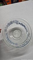 Front view of smaller Pyrex bowl showing blue floral vine pattern around outer side.