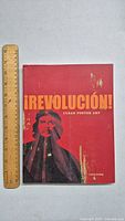 Front cover of ¡Revolución! Cuban Poster Art book with ruler alongside showing size.