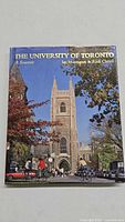 Front cover photo of The University of Toronto souvenir book showing a campus building with a clock tower and people biking.