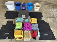 Photo showing the car care kit contents with buckets, microfiber cloths, car mats, cleaning mitts and gloves, scrubbing brush, and car care liquid bottle.