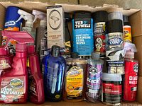 Top view showing many spray bottles including Meguiar's Quick Mist Detailer and Cleaner Wax, Armor All Wash & Wax, Chemical Guys Slick Ceramic Coating, Rust-Oleum Peel Coat and Wheel products, Tub O' Towels wipes, Gunk Engine Degreaser aerosol.