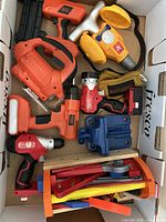 Top-down view of the children’s toy tools showing various pieces such as toy saws, drills, flashlight, hammer, clamp, toy tape measure and tool belt inside a box.