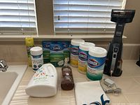 Cleaning products and Black & Decker Dustbuster hand vacuum with charger cable on countertop under window with blinds