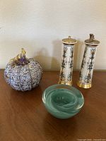Photo of a multicolored decorative glass pumpkin, green hand-blown glass bowl, and Lenox ceramic salt and pepper shakers with gold accents.
