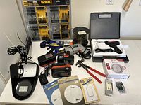 Full view of all items on table showing various tools, electrical hardware, smoke alarm, batteries, wire coils.