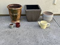 Photo showing all seven garden pots arranged on concrete ground against a cream wall