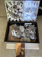 Open LEGO Star Wars Set 4504 box showing loose LEGO pieces in zip bags, with box lid inside showing set assembled image and minifigures guide.