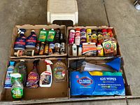 Top view showing mixed multiple cleaning bottles, sprays, a large pack of Clorox disinfecting wipes, and accessories like a blue funnel.