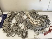 Photo showing various ropes of different materials and colors spread and coiled on a white surface