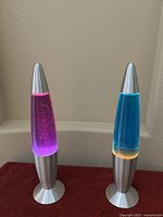 Both lava lamps displayed next to each other on a flat surface showing colors and bases.