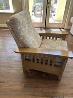 Side view of the craftsman style recliner chair showing oak armrest, cushioned patterned fabric upholstery, and overall design.