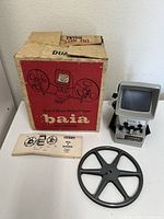 Full view of the Baia Dual 8 Editor and Reviewer unit, original box, manual, and film reel laid out on a floor.