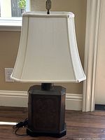 Full view of one vintage metal base lamp with white lampshade and decorative finial