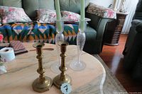 Full view of two brass candlesticks and two taller fine cut crystal glass candlesticks with taper candles on a marble table.