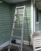 Front view of the aluminum step ladder positioned in A-frame mode with visible red safety locks at the top.