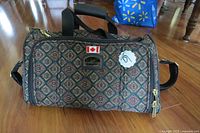 Image showing the full exterior of the Naturalizer carry-on bag on floor, patterned fabric, two short handles, adjustable strap, Canadian flag patch