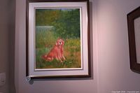 Framed original oil painting depicting a Golden Retriever sitting on grass in a natural setting with trees and flowers in the background. The frame has a white matte and dark wood border.
