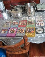All eight seasons of Will and Grace DVDs laid out on table with kitchenware in background. Cases are colorful, show main cast images, and some discs are visible.