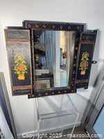 Mirror with shutters open showing floral panels and central glass