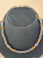 Full view of hematite and coral beaded necklace on display bust