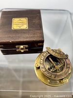 Brass compass-sundial next to closed wooden box