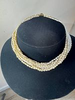 Full view of six-strand pearl necklace on display bust