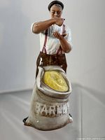 Front view of Royal Doulton Farmer figurine holding grain over barley sack