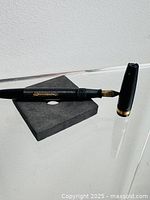 Pen uncapped resting on foam block, showing barrel, section and cap.