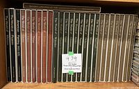 Photo of 26 hardcover art books arranged on a shelf showing spines with titles and authors