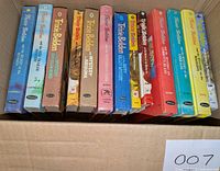 Photo showing 14 Trixie Belden hardcover books in a cardboard box, spines visible with titles and colorful covers.