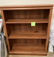 Front view of the brown wooden bookcase showing three shelf sections with two adjustable shelves inside.