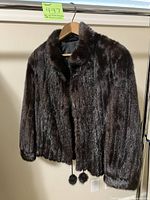 Full front view of dark brown fur jacket on hanger