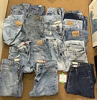 Seventeen pairs of folded GAP blue jeans arranged on a carpeted floor showing various washes and styles for reference.