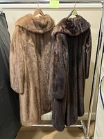 Two fur coats hanging side by side on a garment rack