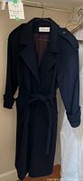 Front view of dark navy long wool jacket with belt and button cuff straps