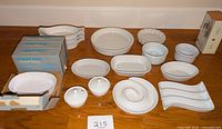 Photo showing the full lot with boxed Corning Ware French White F-15-SP dishes and various other bowls and platters arranged on a table.