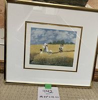 Framed art printed scene showing a woman walking through a wheat field with children, measuring approximately 14.25 inches by 12.25 inches including frame and mat.