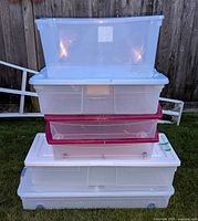 Stack of six transparent plastic storage containers, three with red-tinted sides, two with white lids, and one clear lid