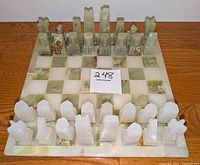 Marble chess board with two full sets of marble pieces arranged on it, note extra off-color white king piece