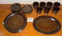 Full set arranged on wooden surface showing 7 large plates (one chipped), 7 saucers, 7 mugs, 1 large oval platter with floral pattern