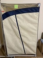 Front view of Rubbermaid clothes wardrobe with zippered beige fabric cover and blue trim.