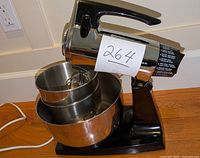 Side angle of Sunbeam Mixmaster stand mixer showing the two nested stainless steel bowls and black base with chrome mixer head.