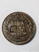 Obverse side showing the Canadian coat of arms with crown and maple leaf wreath, with Latin inscription underneath.