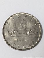 Front side of the 1968 Canadian nickel dollar coin showing the Voyageur canoe design with two paddlers and the Northern Lights.