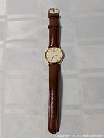 Full view of the Seiko wristwatch lying flat showing the brown leather band and gold-tone round case.