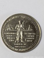 Close-up photo of mining coin showing detailed engravings of miner and mining equipment, listing metals contained.
